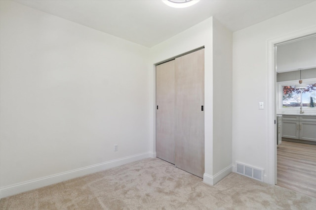 1431 E Oliver St, Owosso, MI 48867 - unfurnished bedroom with light colored carpet, baseboards, and a closet