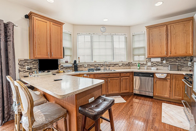 5695 Storrow Ct, Warren, MI 48092 - kitchen featuring stainless steel dishwasher, a sink, a peninsula, a kitchen breakfast bar, and tasteful backsplash