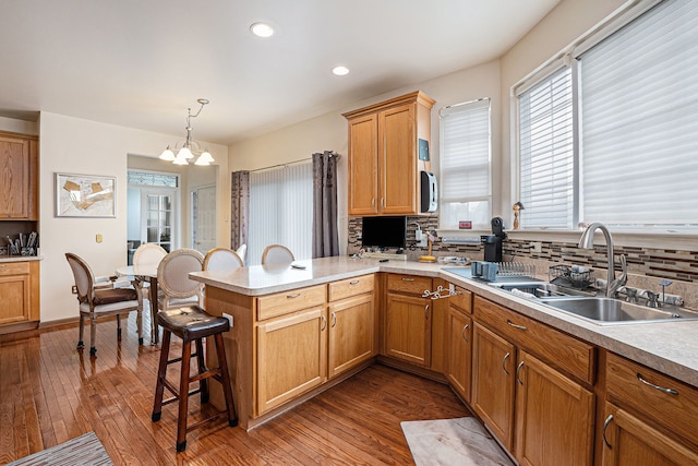 5695 Storrow Ct, Warren, MI 48092 - kitchen with a peninsula, decorative backsplash, a sink, a chandelier, and recessed lighting