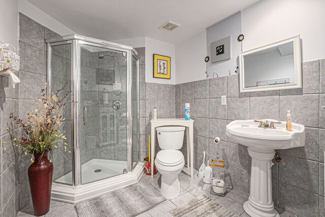 5695 Storrow Ct, Warren, MI 48092 - bathroom with toilet, tile walls, a shower stall, tile patterned floors, and wainscoting