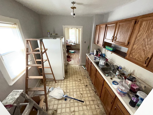 kitchen featuring brown cabinets, light floors, plenty of natural light, and freestanding refrigerator
