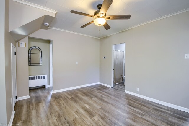 empty room with radiator heating unit, ceiling fan, wood finished floors, baseboards, and crown molding