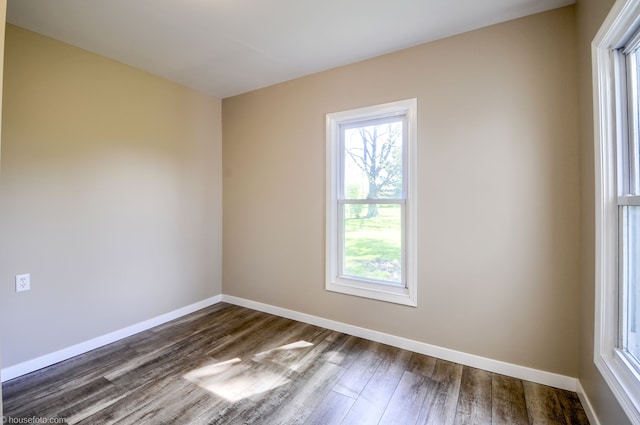 unfurnished room featuring plenty of natural light, dark wood-style floors, and baseboards