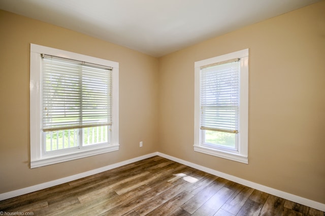 unfurnished room featuring plenty of natural light, baseboards, and dark wood-type flooring