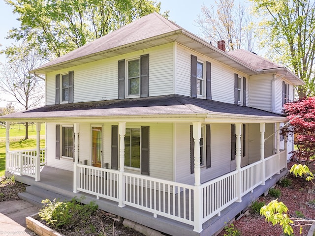 farmhouse inspired home with a porch, a chimney, and roof with shingles
