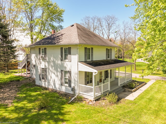 rear view of property with covered porch, a chimney, a shingled roof, and a yard