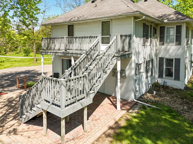 back of house with stairs, roof with shingles, a patio area, and a wooden deck