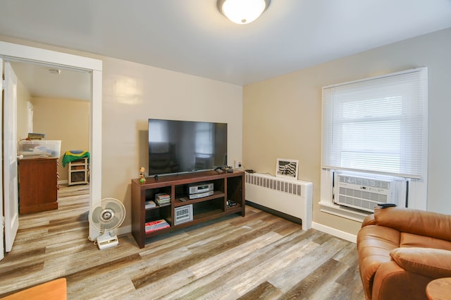 living area featuring radiator heating unit, wood finished floors, baseboards, and cooling unit