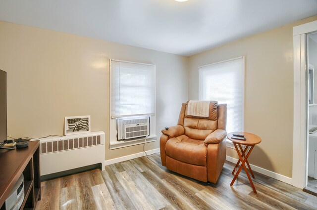 living area featuring radiator heating unit, wood finished floors, baseboards, and cooling unit