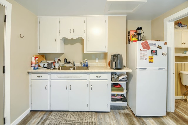 kitchen with freestanding refrigerator, light wood-type flooring, a sink, and light countertops