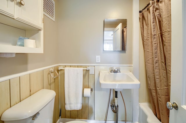 bathroom with a wainscoted wall and toilet