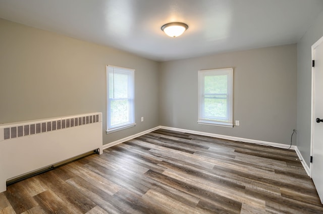 empty room with radiator heating unit, plenty of natural light, and dark wood finished floors