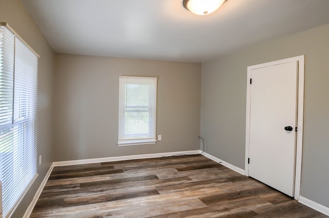 unfurnished room with dark wood-type flooring and baseboards