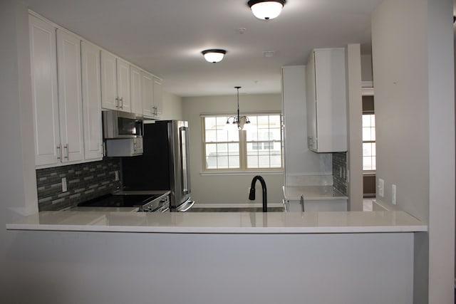414 Old Pine Way Unit 136, Walled Lake, MI 48390 - kitchen with stainless steel appliances, decorative backsplash, a peninsula, white cabinetry, and decorative light fixtures
