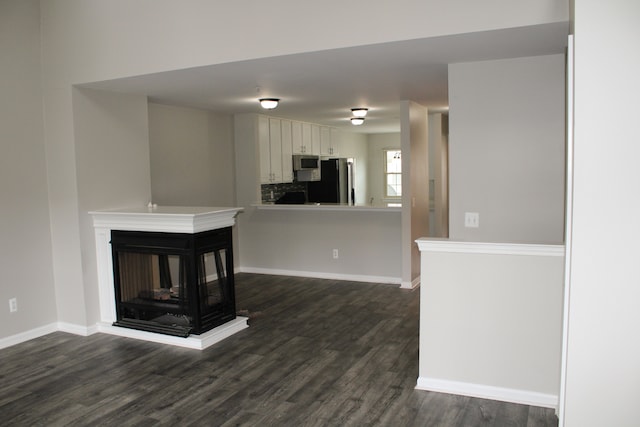 414 Old Pine Way Unit 136, Walled Lake, MI 48390 - unfurnished living room featuring dark wood-style flooring, baseboards, and a multi sided fireplace