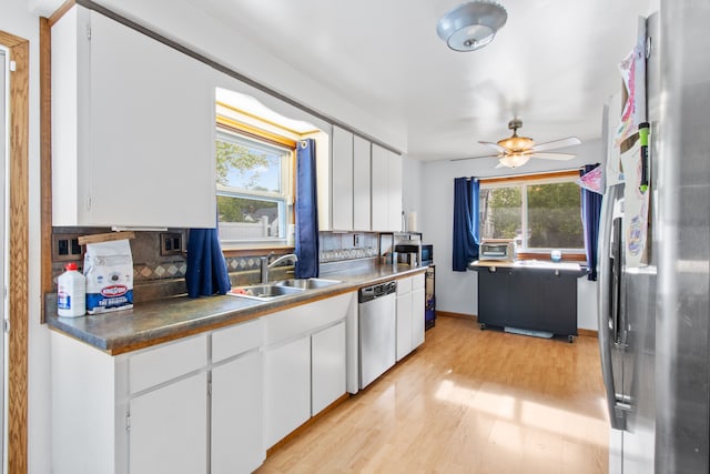 kitchen featuring stainless steel appliances, light wood-style flooring, tasteful backsplash, ceiling fan, and a sink
