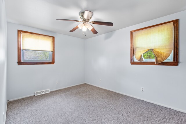 carpeted spare room featuring a ceiling fan and baseboards