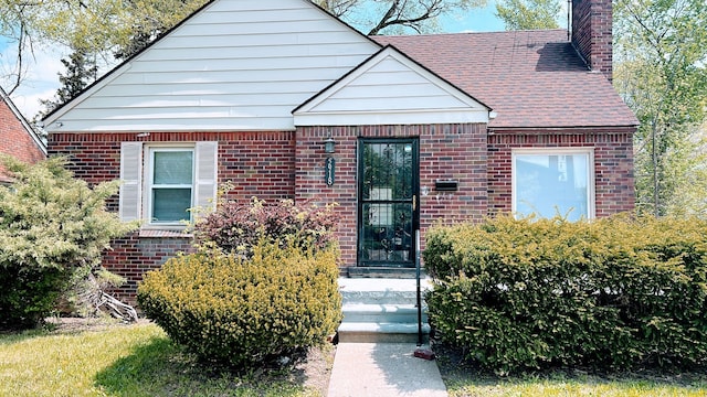 view of front of house featuring a chimney and brick siding