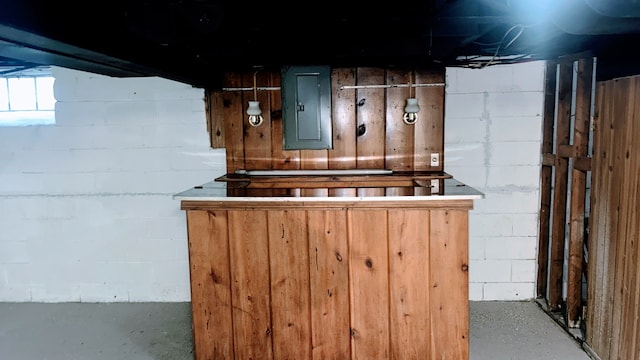 below grade area featuring electric panel, a dry bar, and concrete block wall