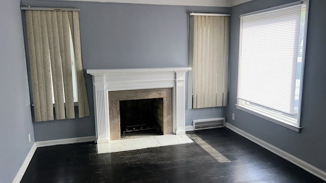 unfurnished living room featuring dark wood-style flooring, baseboards, and a fireplace with flush hearth