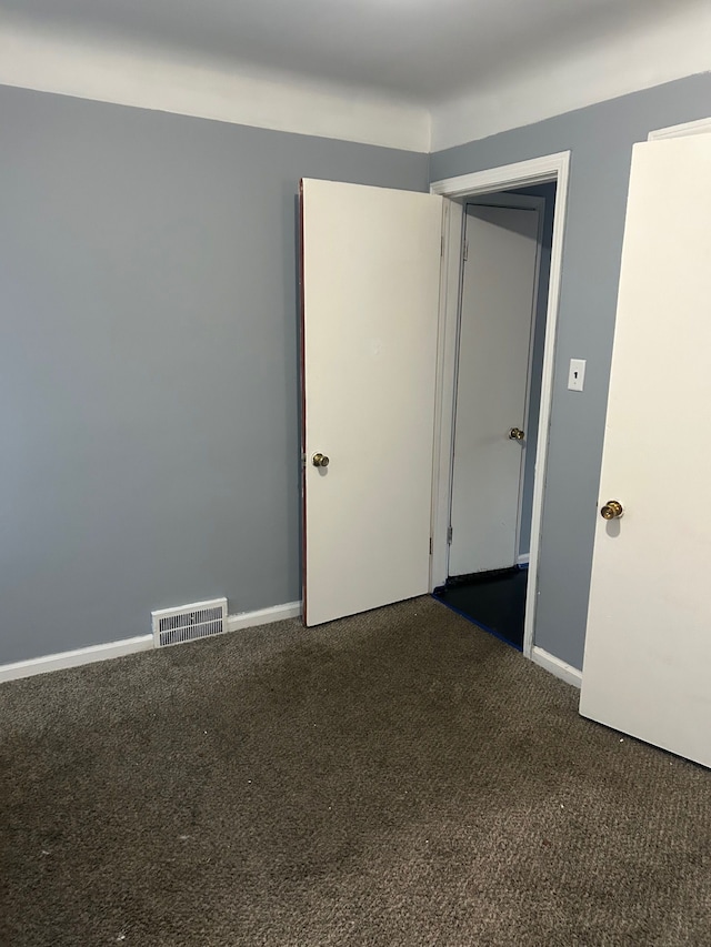 empty room with dark colored carpet and baseboards