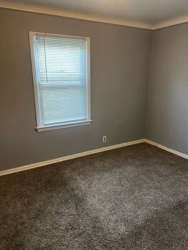 carpeted empty room featuring baseboards
