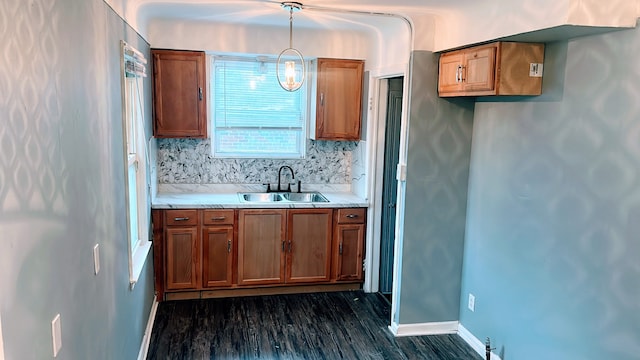 kitchen featuring a sink, baseboards, light countertops, dark wood finished floors, and brown cabinetry