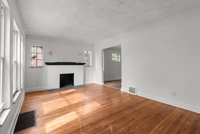 unfurnished living room featuring wood finished floors, a fireplace, baseboards, and a textured ceiling