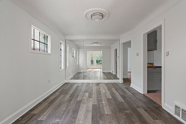 corridor with dark wood finished floors, baseboards, and ornamental molding