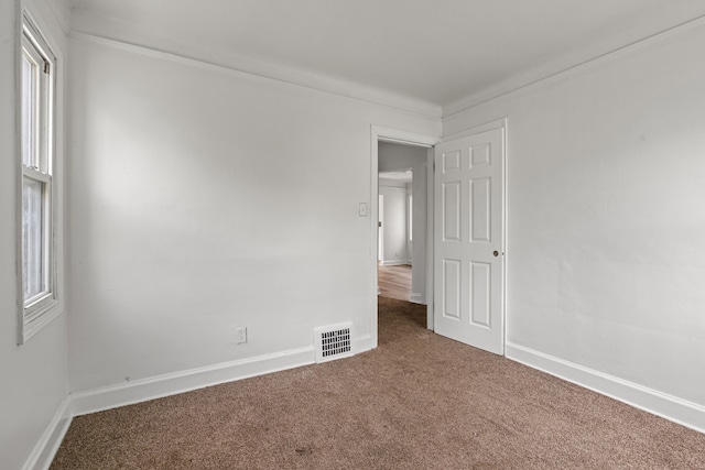 spare room featuring carpet floors, baseboards, and ornamental molding