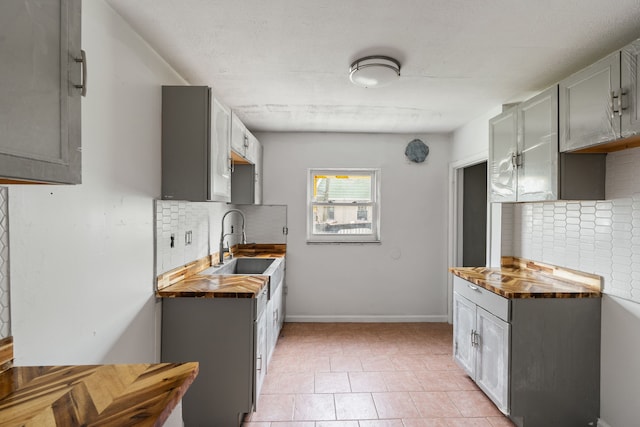 kitchen featuring tasteful backsplash, gray cabinets, and a sink