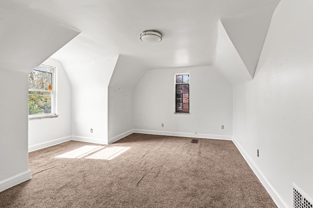 bonus room with carpet floors, healthy amount of natural light, vaulted ceiling, and baseboards