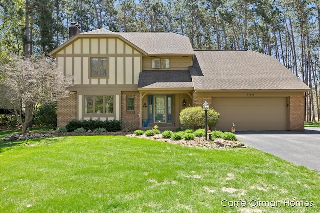 17134 Timber Dunes Dr, Grand Haven, MI 49417 - view of front facade with brick siding, a shingled roof, a garage, asphalt driveway, and a front yard