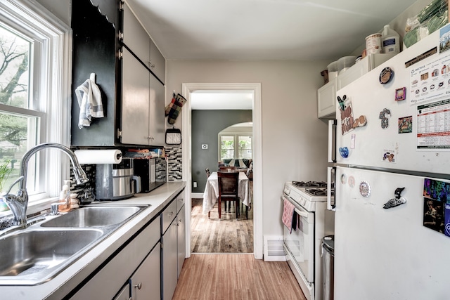 132 Jerome Ave, Ypsilanti, MI 48198 - kitchen featuring white appliances, a sink, light wood-type flooring, arched walkways, and light countertops
