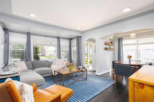living area featuring dark wood finished floors, baseboards, arched walkways, and recessed lighting