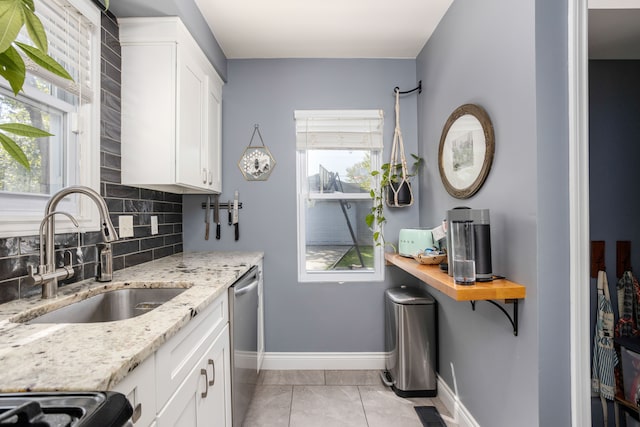 kitchen with stainless steel dishwasher, a sink, decorative backsplash, and healthy amount of natural light