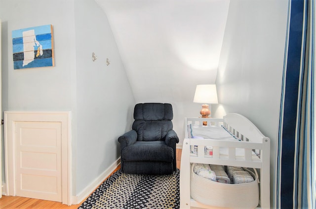 living area with baseboards, lofted ceiling, and wood finished floors