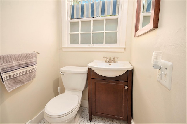 half bathroom with baseboards, toilet, and vanity