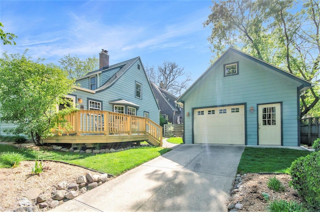 view of front of home with a deck, driveway, an outbuilding, a chimney, and a garage