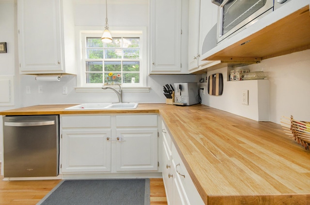 kitchen with butcher block countertops, appliances with stainless steel finishes, a sink, light wood-style floors, and white cabinets