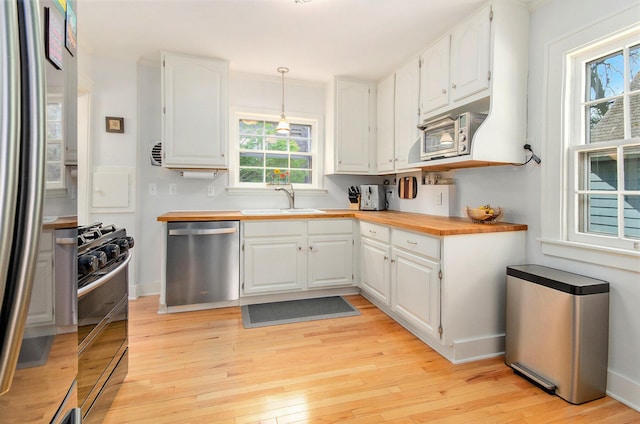 kitchen with stainless steel appliances, wood counters, a sink, light wood finished floors, and white cabinets