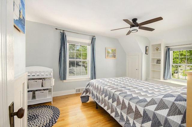 bedroom featuring wood finished floors, multiple windows, baseboards, a ceiling fan, and vaulted ceiling