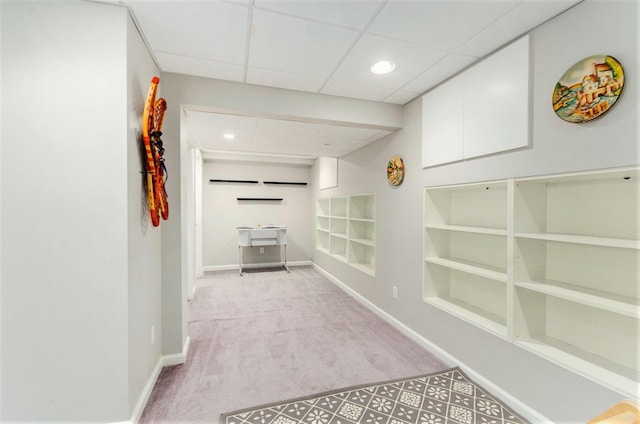 hall with light colored carpet, built in shelves, baseboards, recessed lighting, and a paneled ceiling
