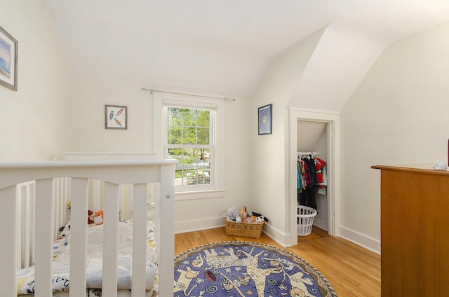 bedroom with lofted ceiling, wood finished floors, and baseboards