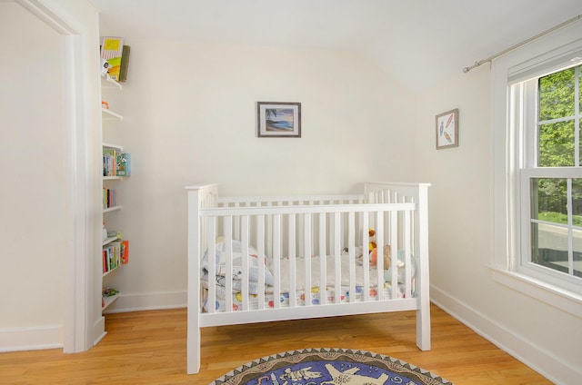 bedroom with wood finished floors, lofted ceiling, and baseboards