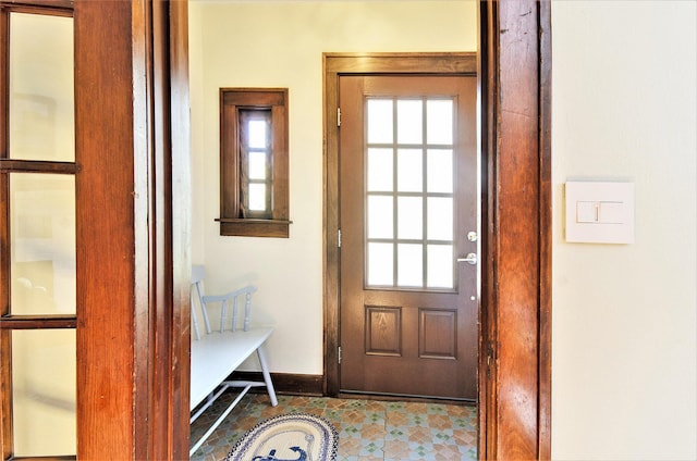 doorway with baseboards and tile patterned flooring