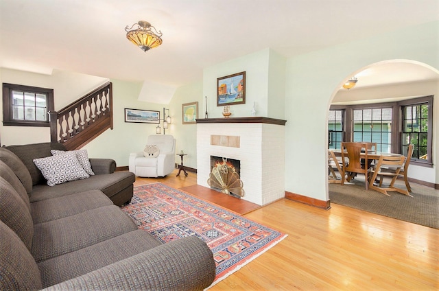 living room with arched walkways, wood finished floors, healthy amount of natural light, and baseboards