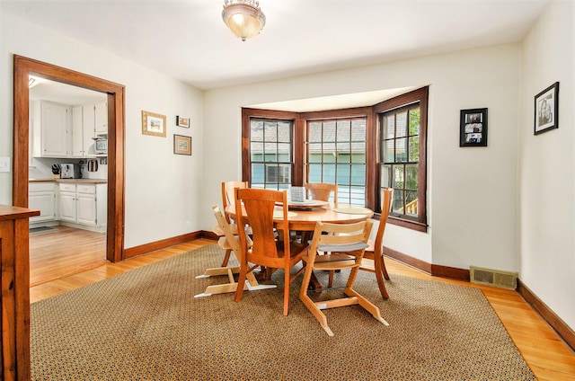 dining space featuring light wood-type flooring and baseboards