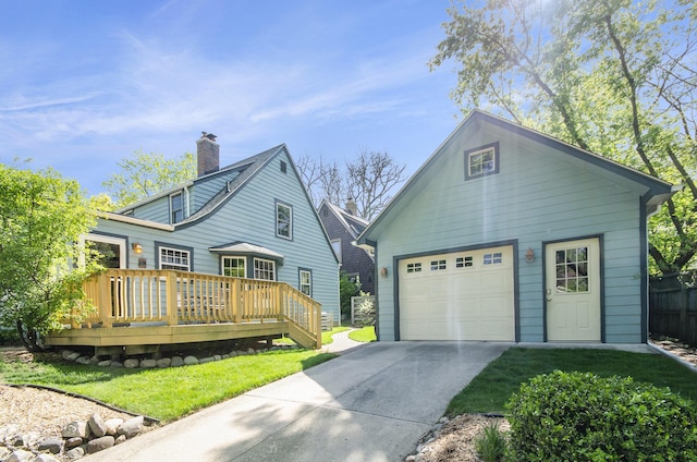 view of front of home with a wooden deck, driveway, an outbuilding, and a front yard