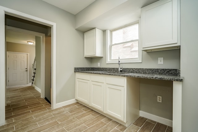 17344 Wisconsin St, Detroit, MI 48221 - kitchen with a sink, light wood-style floors, baseboards, white cabinets, and dark stone counters